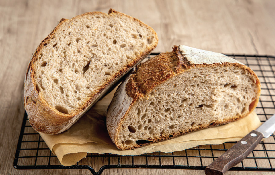 bread roll cut in half on cloth and cleaning rack next to knife