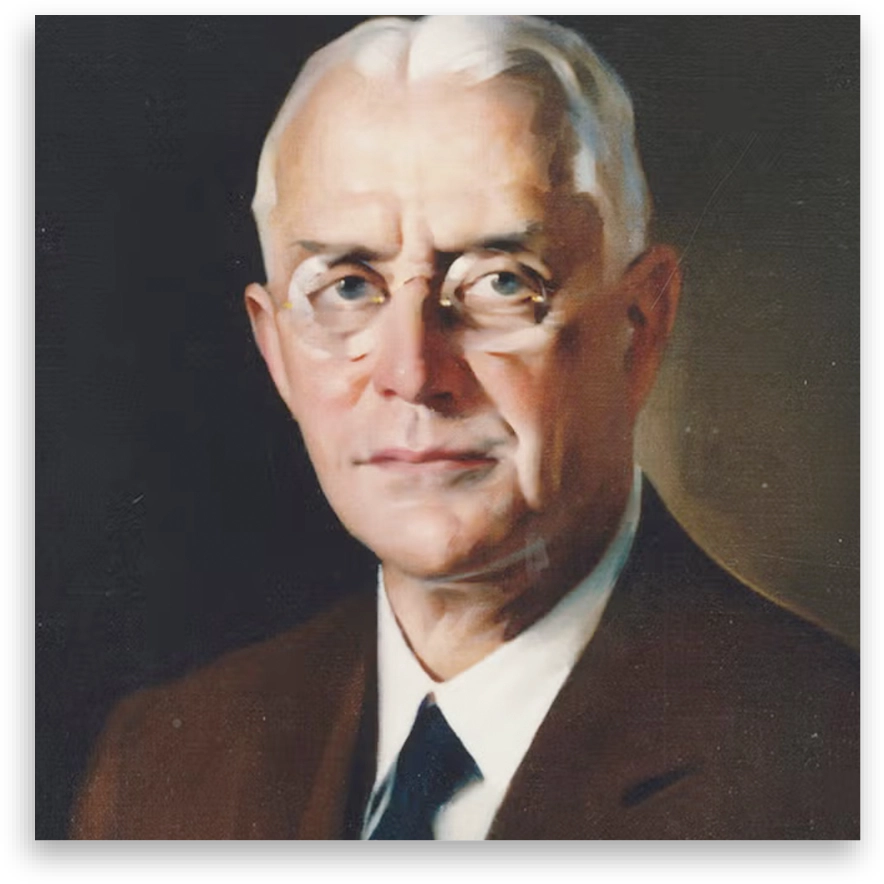 Portrait of an older person with glasses, wearing a suit, against a dark background with a patterned border.