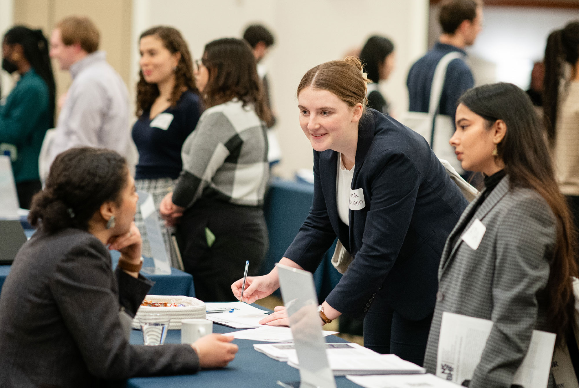 two female students talking to woman at booth
