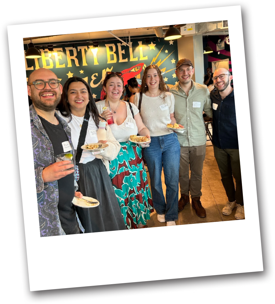 students and alumni standing for group photo while holding plates of food